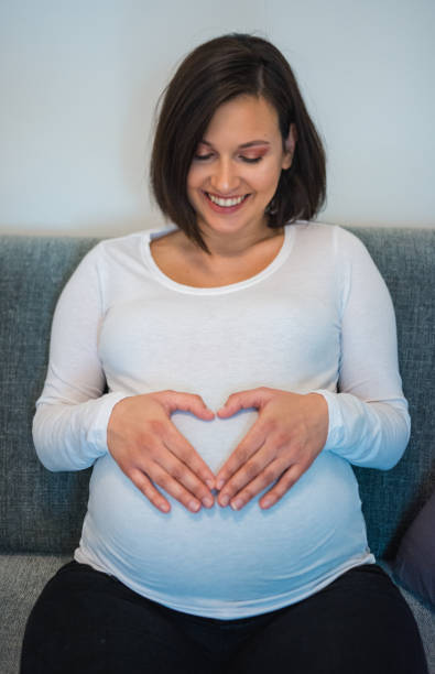 istock Woman making a heart shape on her pregnant belly 906396320