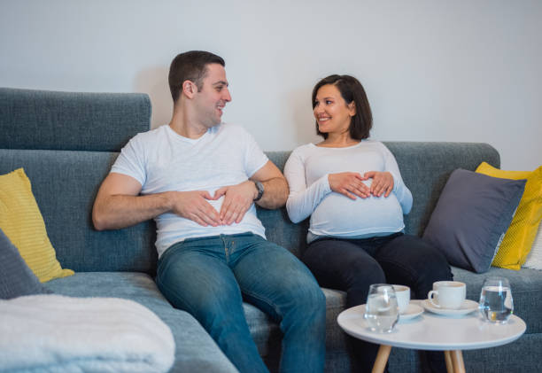 istock Man and wife making a heart shape on their bellies 906396404