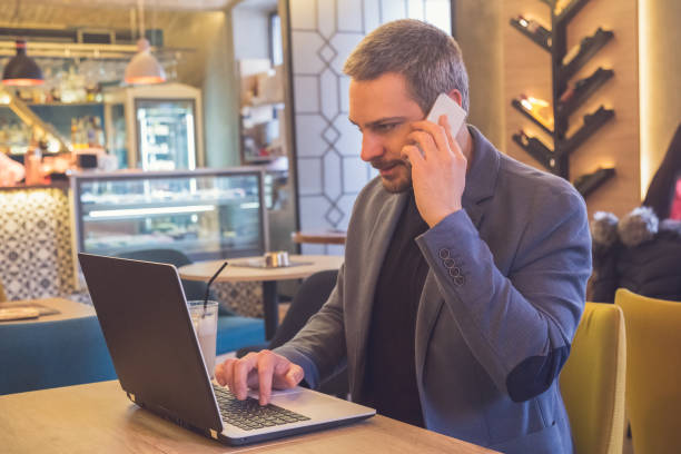 istock Businessman working in laptop and talking on cellphone in cafe 906410584