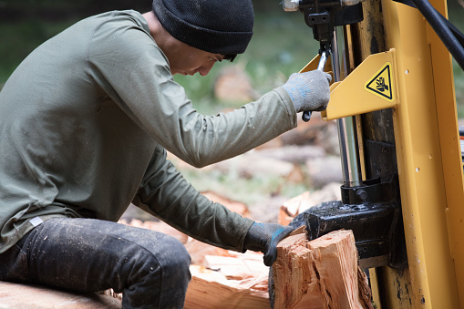 Man cutting firewood with wood splitter