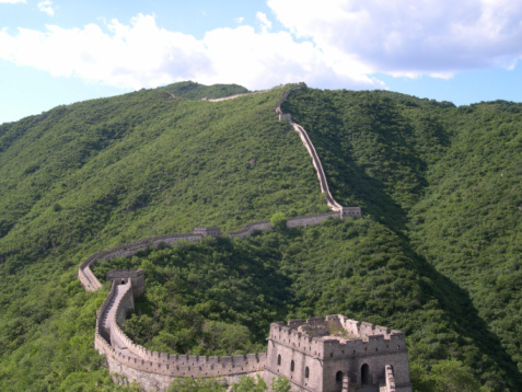 Great Wall in the lush mountains at Mutianyu, China, from a distance in the summer on a clear, blue sky day