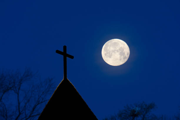 istock Church steeple silhouette and moon with copy space 906465134