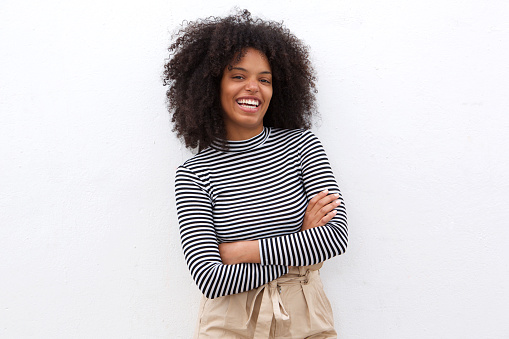 Portrait of smiling black woman in striped shirt with arms crossed