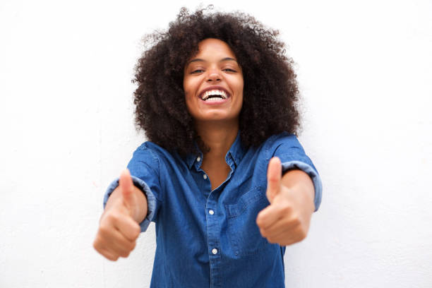 istock smiling black woman with two thumbs up against white background 906496336