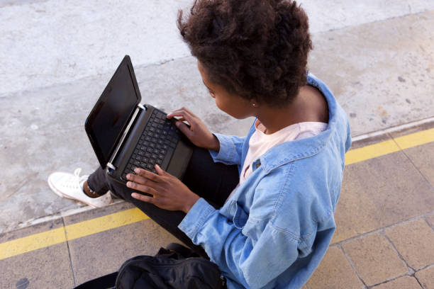 istock Top view young african american woman sitting outside using laptop 906498464