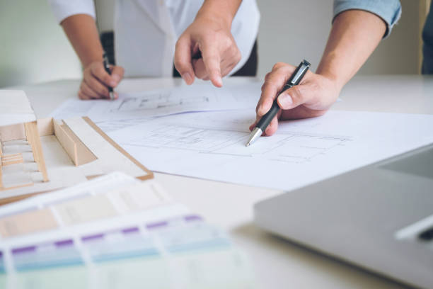 istock Two interior design or graphic designer at work on project of architecture drawing with work tools and color swatches, colour chart, color samples for selection, renovation and technology concept 906511746