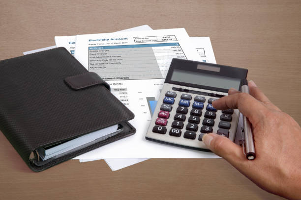 Someone using calculator to summarize amount of electricity cost.