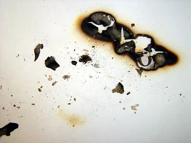 burn marks and ashes on sheet of paper