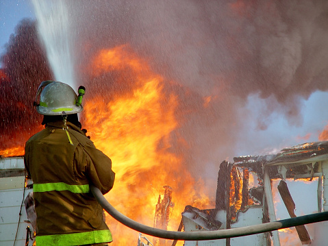 A fireman hoses down a burning home