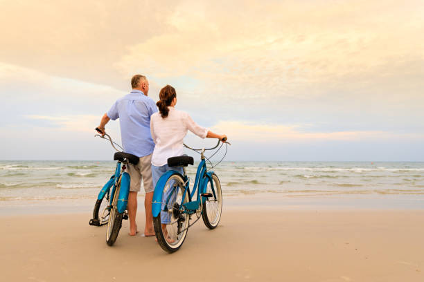 couple actif avec vélos - senior couple cycling beach bicycle photos et images de collection