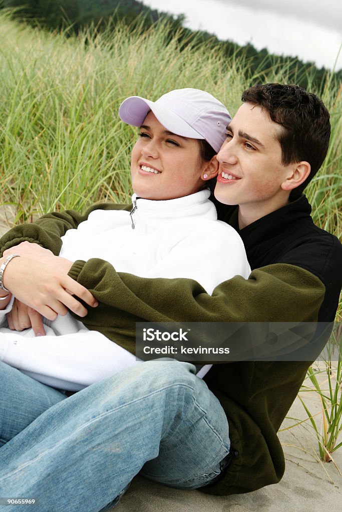 Giovane coppia rilassante sulla spiaggia - Foto stock royalty-free di Abbigliamento casual