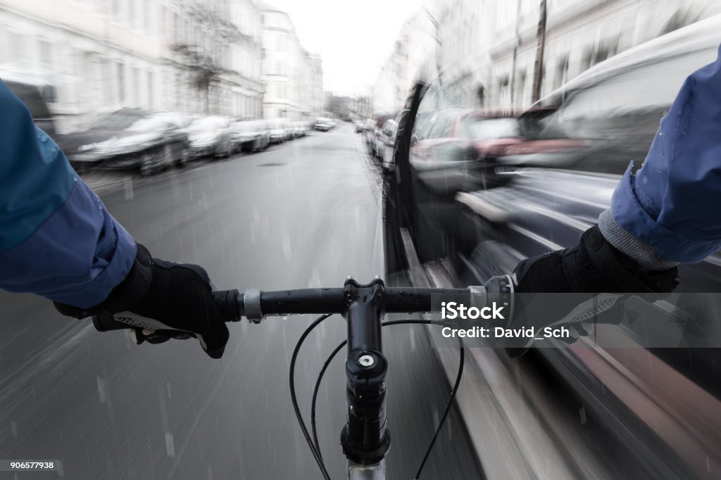 Car-dooring -- Cyclist in the rain on collision course with car door Car-dooring -- Cyclist on a collision course with car door Cycling Stock Photo