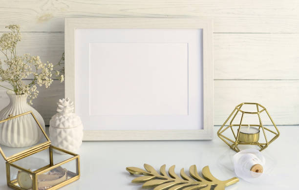 istock White frame mockup with interior items on white wooden background. Poster product design styled mock-up.Copy space 906580462