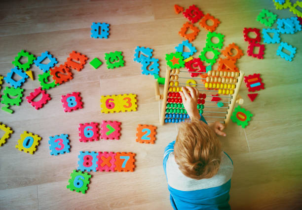 istock little boy calculating on abacus, playing with number puzzle 906594118