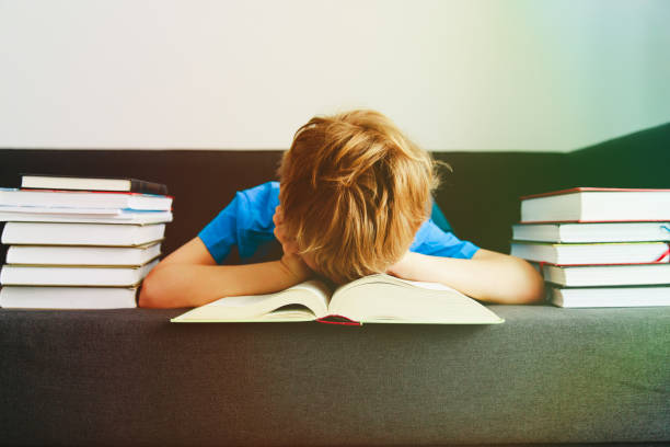 istock little boy tired stressed of reading, doing homework 906597172