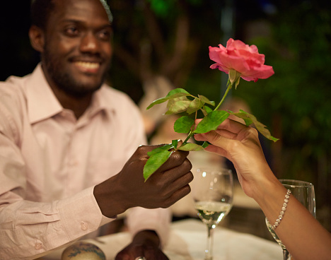 Cropped shot of a man giving his girlfriend a rose while out on a date