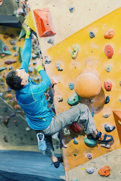 istock Young man practicing rock-climbing on a rock wall indoors. 906600226