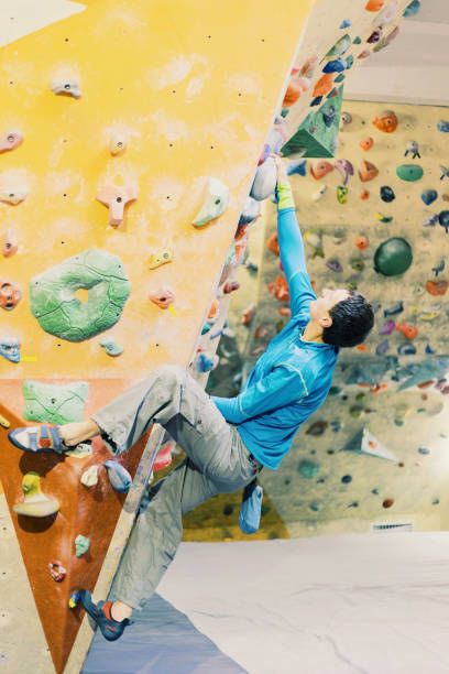 istock Young man practicing rock-climbing on a rock wall indoors. 906600398