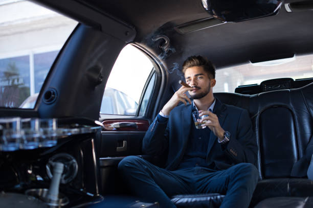 istock Young businessman enjoying cigar in limo 906612080