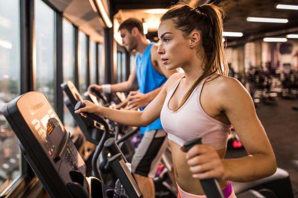 istock Determined woman exercising on a cross trainer in a gym. 906612548
