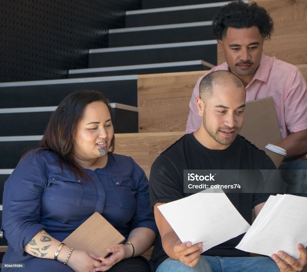 Ethnically diverse group of employees in business work place having a team meeting reviewing a document. Ethnically diverse group of employees in business work place having a serious team meeting reviewing a document. Photographed in Auckalnd, New Zealand, NZ. Corporate Business Stock Photo