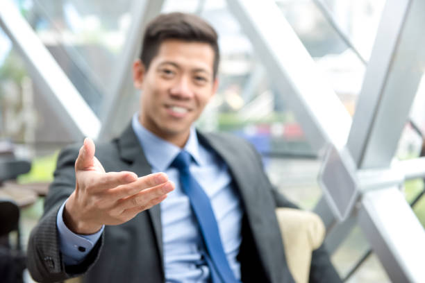 istock Friendly Asian businessman reaching out hand with open palm, welcome gesture 906621576