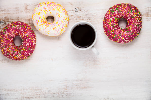 Donuts and a cup of coffee Donuts and a cup of coffee on a wooden background, top view. Delicious breakfast. alcorza stock pictures, royalty-free photos & images