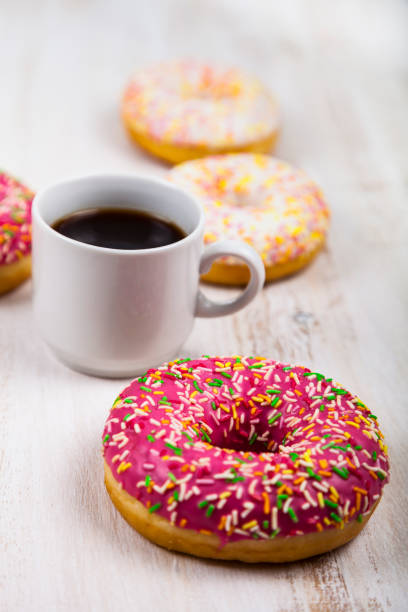 Donuts and a cup of coffee Donuts and a cup of coffee on a wooden background, top view. Delicious breakfast. alcorza stock pictures, royalty-free photos & images