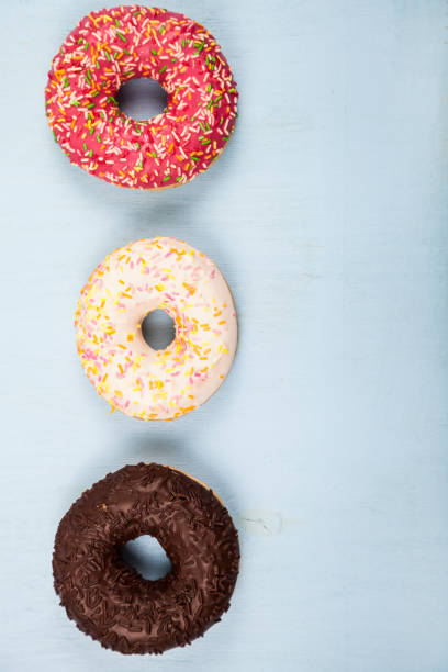 Multicolored donuts close-up Multicolored donuts close-up on a blue wooden background. Delicious dessert. alcorza stock pictures, royalty-free photos & images