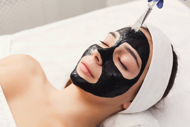 istock Woman gets face mask by beautician at spa 906640868