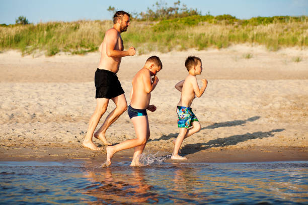 Father and sons are jogging in the beach. stock photo