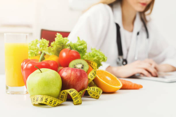 Nutritionist desk with fruit and measuring tape Nutritionist desk with healthy fruit, juice and measuring tape. Dietitian working on diet plan. Weight loss and right nutrition concept serving sport stock pictures, royalty-free photos & images