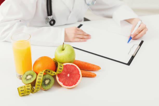 istock Nutritionist desk with fruit and measuring tape 906647634