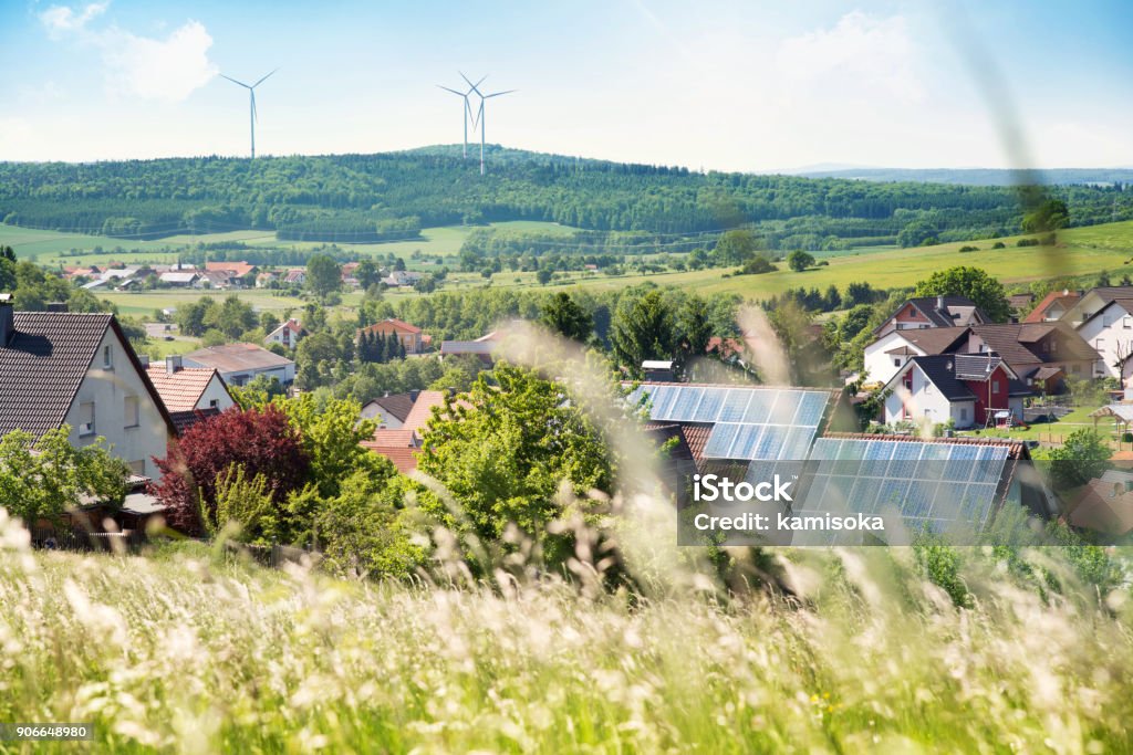 House with solar panels on the roof and wind turbines House Stock Photo