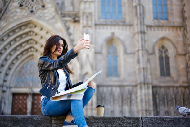 istock Beautiful young woman taking picture using smartphone posing on ancient architecture background, charming brunette female tourist making selfie on mobile  for travel blog enjoying weekend journey 906651802