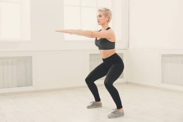 istock Young beautiful woman in sportswear doing squat 906651946
