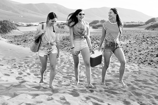 Young stylish models walking on beach going for picnic and laughing happily.