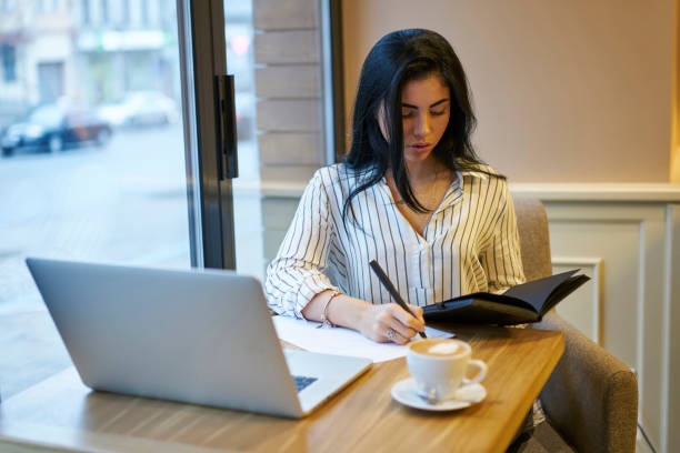 istock Attractive businesswoman concentrated on writing documents checking financial information in notebook, professional marketing expert creating planning for project strategy doing remote job in cafe 906655182