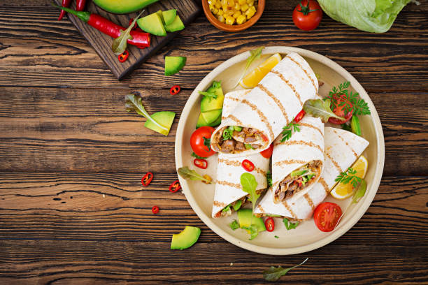 Burritos wraps with beef and vegetables on a wooden background. Beef burrito , mexican food. Healthy food background. Mexican cuisine.Top view.