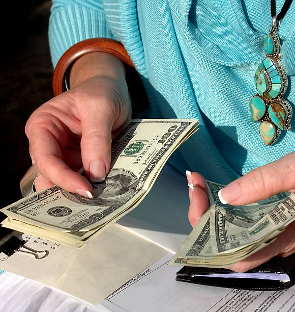 A close-up of a woman in turquoise handling money stock photo