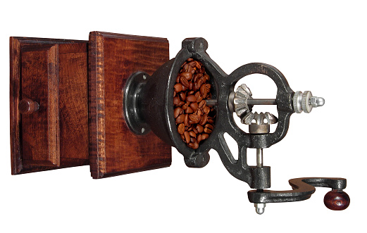 Filter bag with ground coffee, manual coffee grinder on a white isolated background. Copy space. Coffee beans laid out on the surface in the shape of a heart.