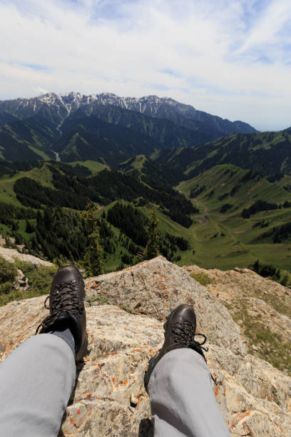istock Hiker legs sit on mountain top cliff edge 906716150