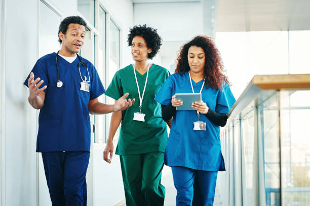 groupe de professionnels médicaux, discutant le long du couloir de l’hôpital - healthcare and medicine smiling group of people lab coat photos et images de collection