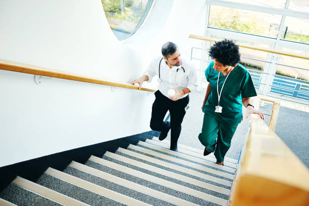 Two doctors on staircase having conversation Two medical doctors on staircase having conversation over a case in hospital doctor lifestyle stock pictures, royalty-free photos & images