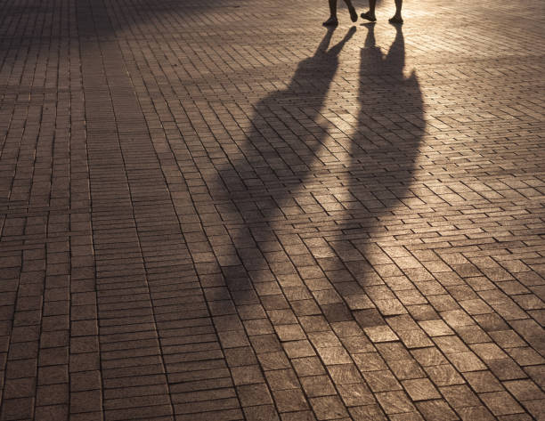 Shadow of two people on sidewalk in dark. Back lit is used. Shot with a full frame DSLR camera.