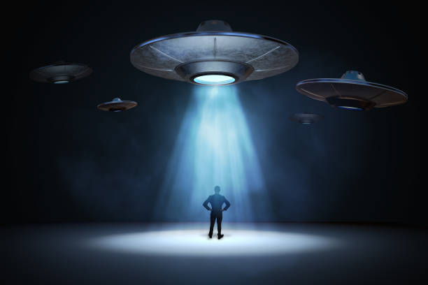 istock Alien invasion concept. Man standing under light beam from flying UFO spaceship. 3D rendered illustration. 906720132