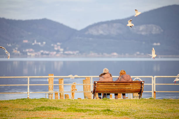 älteres ehepaar sitzt auf einer bank am ufer des lago massaciuccoli - contemplation sunset eternity thinking stock-fotos und bilder