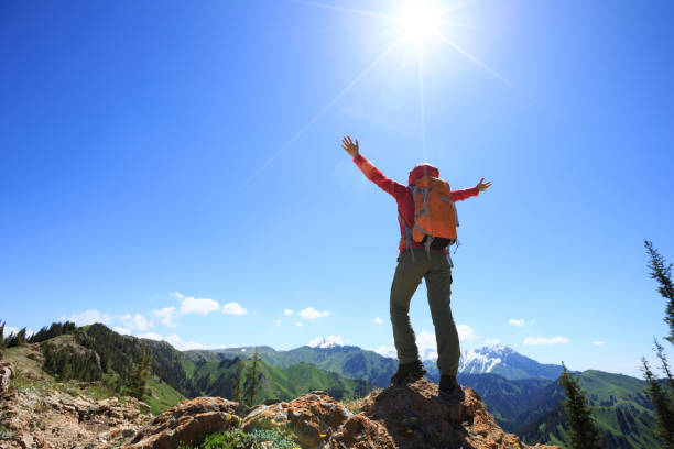istock successful Hiker outstretched arms stand at cliff edge on mountain top 906726516