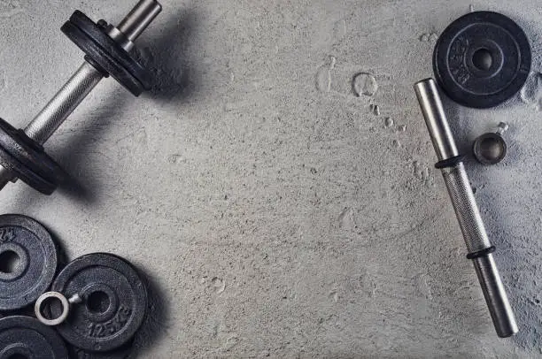 Fitness or bodybuilding concept background. Product photograph of old iron dumbbells on grey, conrete floor in the gym. Photograph taken from above, top view with lots of copy space