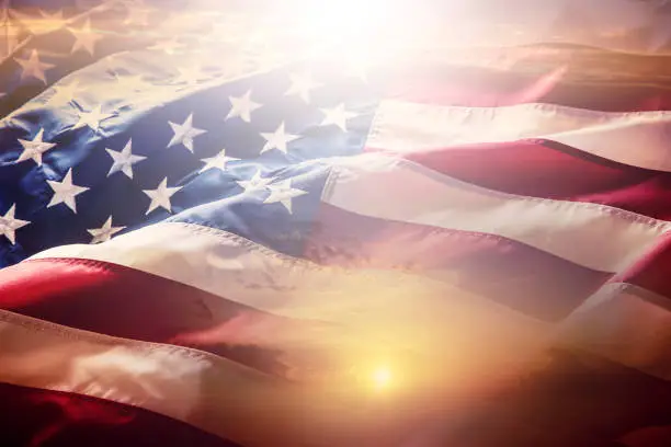 Photo of USA flag. American flag. American flag blowing wind at sunset or sunrise. Close-up